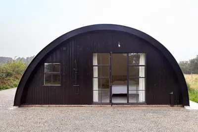 a black shed with a door in the middle at Converted Nissen Barn on beautiful farm in Braintree