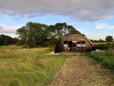 a small building in the middle of a field at Converted Nissen Barn on beautiful farm in Braintree