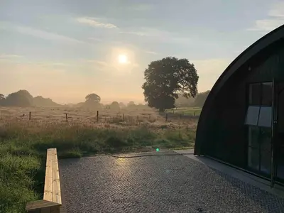 a tent in a field with the sunset in the background at Converted Nissen Barn on beautiful farm in Braintree
