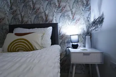 a bedroom with a bed and a night stand with a lamp at Comfy Town Centre Apartment Free Parking WiFi in Colchester