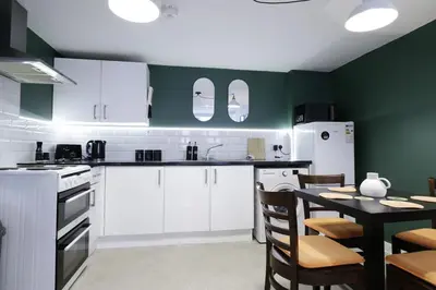 a kitchen with white cabinets and a table with chairs at Comfy Town Centre Apartment Free Parking WiFi in Colchester