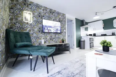 a living room with a green chair and a kitchen at Comfy Town Centre Apartment Free Parking WiFi in Colchester