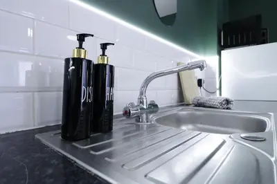 two black bottles sitting on a kitchen sink at Comfy Town Centre Apartment Free Parking WiFi in Colchester