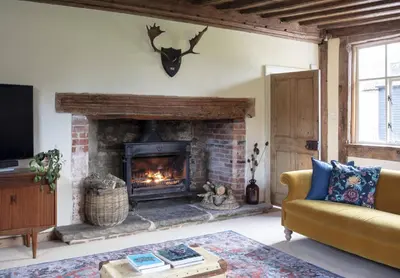 a living room with a fireplace and a couch at Farmhouse in Suffolk with wild swimming & hot tub in Saint Margaret