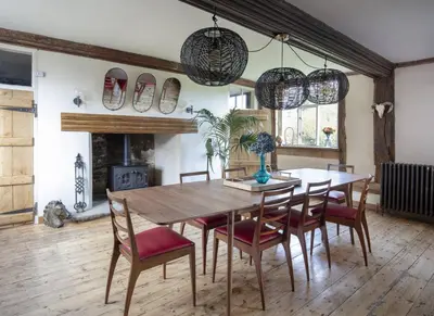 a dining room with a table and chairs and a fireplace at Farmhouse in Suffolk with wild swimming & hot tub in Saint Margaret