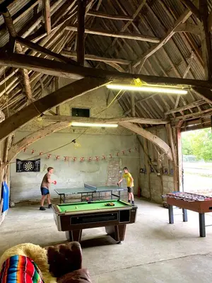 two men playing a game of pool in a barn at Farmhouse in Suffolk with wild swimming & hot tub in Saint Margaret