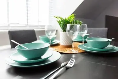 a table with green bowls and plates and wine glasses at 1 Bed Split Level Apartment- Leigh-on-Sea in Southend-on-Sea