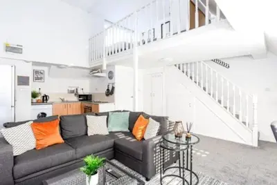 a living room with a couch and a staircase at 1 Bed Split Level Apartment- Leigh-on-Sea in Southend-on-Sea