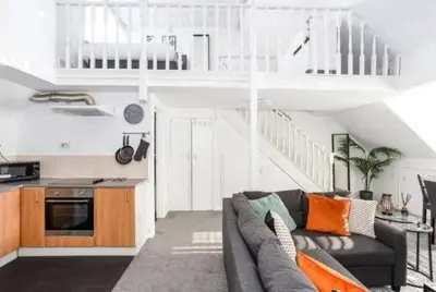 a living room with a couch and a staircase at 1 Bed Split Level Apartment- Leigh-on-Sea in Southend-on-Sea