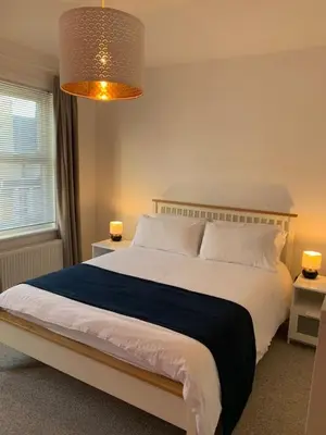 a bedroom with a large bed and a chandelier at 3 Bed Family House Free Parking in Southend-on-Sea