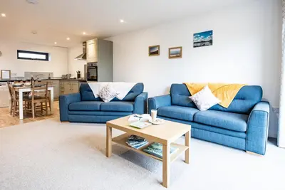 a living room with two blue couches and a table at Grove Farm Cottage, Worlingworth in Worlingworth