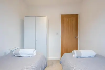 a bedroom with two beds with white walls and a door at Grove Farm Cottage, Worlingworth in Worlingworth