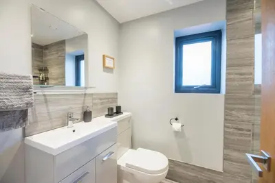 a bathroom with a toilet and a sink and a mirror at Grove Farm Cottage, Worlingworth in Worlingworth