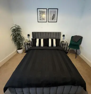 a bedroom with a black bed and a green chair at Cosy Home in Chelmsford City, Free WiFi & Free Parking - Mildmay House by Stays Accommodation - Long Stays Welcome in Chelmsford