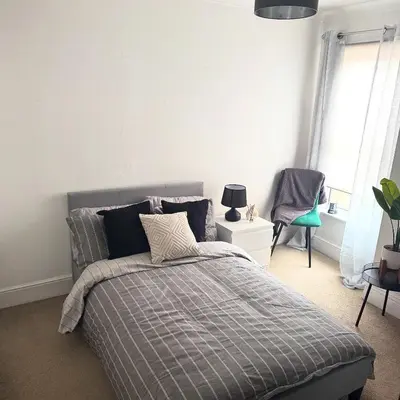 a bedroom with a bed and a chair in it at Cosy Home in Chelmsford City, Free WiFi & Free Parking - Mildmay House by Stays Accommodation - Long Stays Welcome in Chelmsford