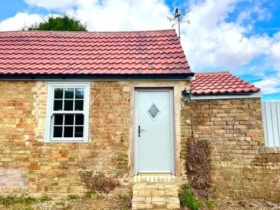 a brick house with a white door and a red roof at Outbuilding with river views in Cambridgeshire in Holywell