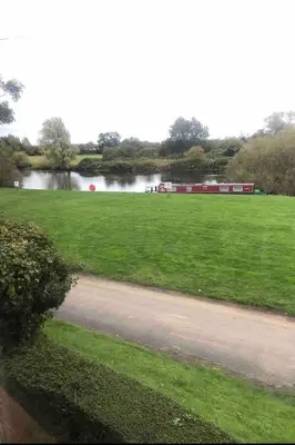 a field with a river and a train in the distance at Outbuilding with river views in Cambridgeshire in Holywell
