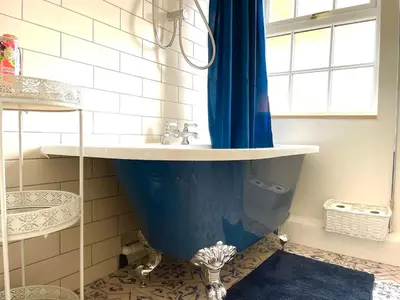 a bathroom with a sink and a blue shower curtain at Outbuilding with river views in Cambridgeshire in Holywell