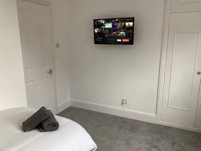 a bedroom with a bed and a tv on the wall at Brackens House Brentwood in Little Warley
