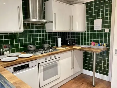 a kitchen with green tiled walls and white appliances at Brackens House Brentwood in Little Warley