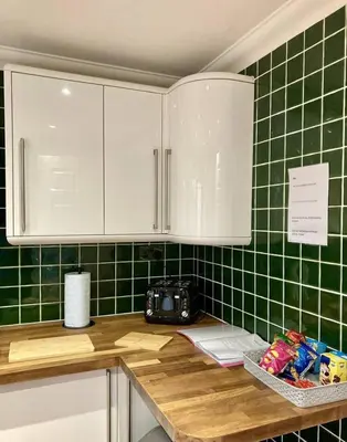 a kitchen counter with green tiled walls and white cabinets at Brackens House Brentwood in Little Warley