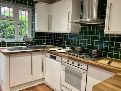 a kitchen with white cabinets and green tiles at Brackens House Brentwood in Little Warley