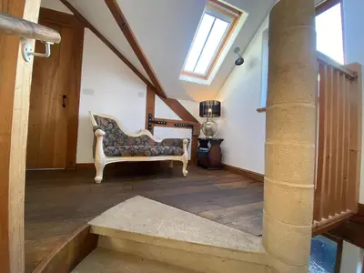 a living room with a chair and a staircase at Charming 2-Bedroom Cottage in Cambridgeshire in West Wratting