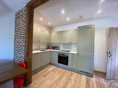 a kitchen with white cabinets and a brick wall at Charming 2-Bedroom Cottage in Cambridgeshire in West Wratting