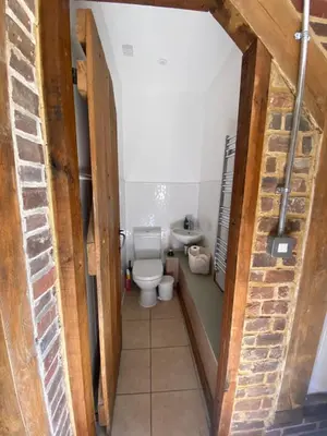 a small bathroom with a toilet and a brick wall at Charming 2-Bedroom Cottage in Cambridgeshire in West Wratting