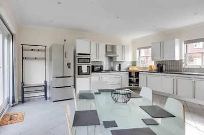 a kitchen with a glass table and white appliances at Elizabeth Four Bedroom Townhouse in Bocking Churchstreet