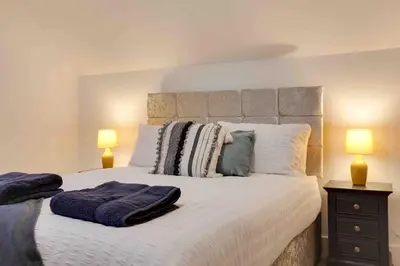 a bedroom with a large bed with two lamps at Foxglove House & Hot Tub Stansted Airport in London Stansted Airport