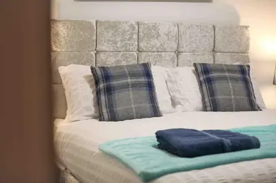 a bed with pillows and a blue towel on it at Foxglove House & Hot Tub Stansted Airport in London Stansted Airport