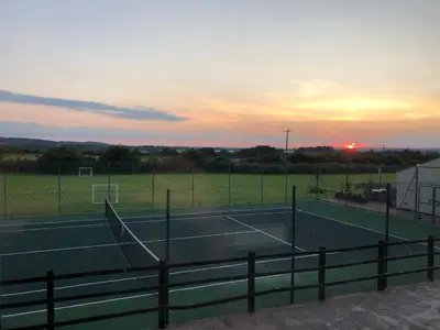 a tennis court with the sunset in the background at An Escape to the Country in Rochford