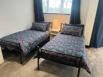 two beds in a room with blue curtains at An Escape to the Country in Rochford