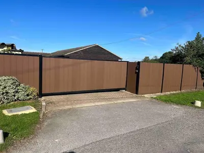 a wooden fence with a driveway in front of a house at An Escape to the Country in Rochford