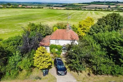 an aerial view of a house with a car parked in front at Charming 3 Bedroom Detached Cottage With Garage in Wormley