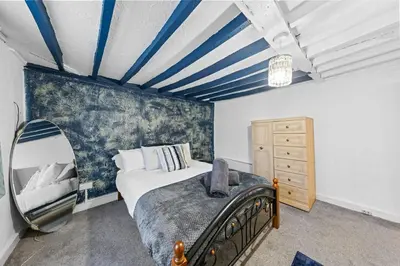 a bedroom with a large bed and a mirror at Charming 3 Bedroom Detached Cottage With Garage in Wormley