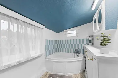 a bathroom with a white tub and a blue ceiling at Charming 3 Bedroom Detached Cottage With Garage in Wormley