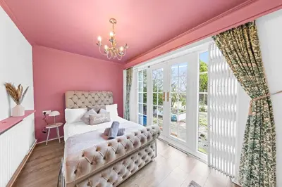 a bedroom with pink walls and a bed and a window at Charming 3 Bedroom Detached Cottage With Garage in Wormley
