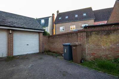 a brick wall with a trash can next to a garage at Holly Close in Ipswich