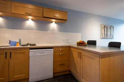 a kitchen with wooden cabinets and a white dishwasher at Holly Close in Ipswich