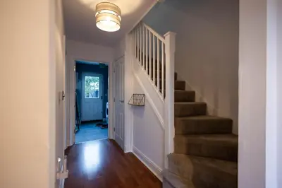 a hallway with a staircase with a light fixture at Holly Close in Ipswich