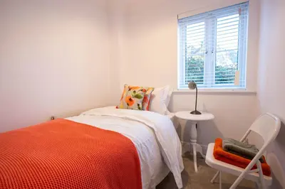 a bedroom with a bed and a chair and a window at Holly Close in Ipswich