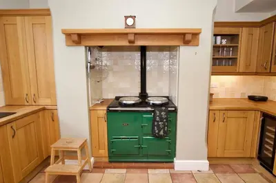 a green stove in a kitchen with wooden cabinets at Beautiful country home and garden in Kirby Cross
