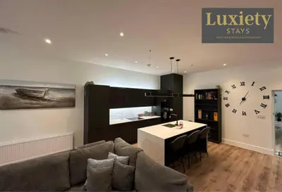 a living room with a couch and a clock on the wall at Sleek & Stunning 2BR APT By Luxiety Stays Short Lets & Serviced Accommodation Southend on sea With Free WiFi, Smart TV, Netflix in Southend-on-Sea