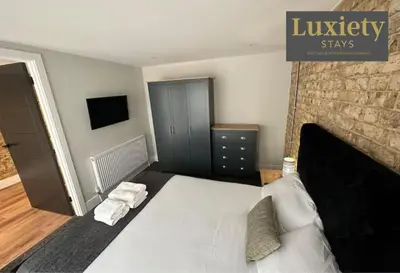 a bedroom with a large white bed and a brick wall at Sleek & Stunning 2BR APT By Luxiety Stays Short Lets & Serviced Accommodation Southend on sea With Free WiFi, Smart TV, Netflix in Southend-on-Sea