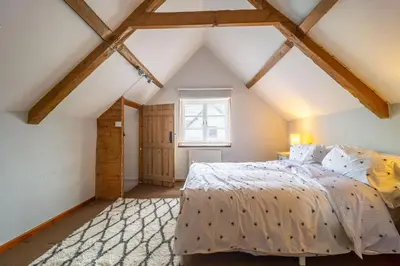 a bedroom with a large bed in a attic at Swift Host - 2 Bedrooms - Period Cottage - Garden - Village Location - Dog Friendly in Hockham