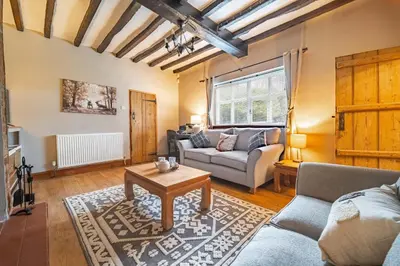 a living room with a couch and a table at Swift Host - 2 Bedrooms - Period Cottage - Garden - Village Location - Dog Friendly in Hockham