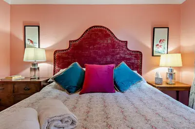 a bedroom with a bed with colorful pillows and two lamps at 1 Bed in Wymondham oc-w30597 in Wymondham