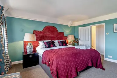 a bedroom with a large bed with a red headboard at 6 Bed in Wymondham oc-t30598 in Wymondham